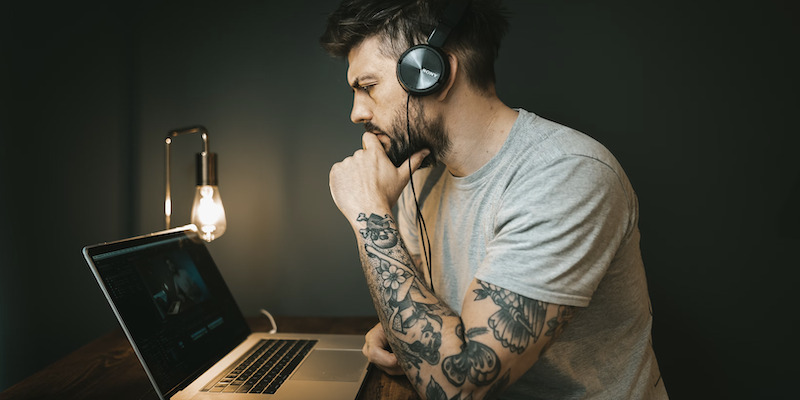 tattooed-worker-with-headphones-on-laptop